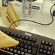 Person holds sandwich over computer keyboard